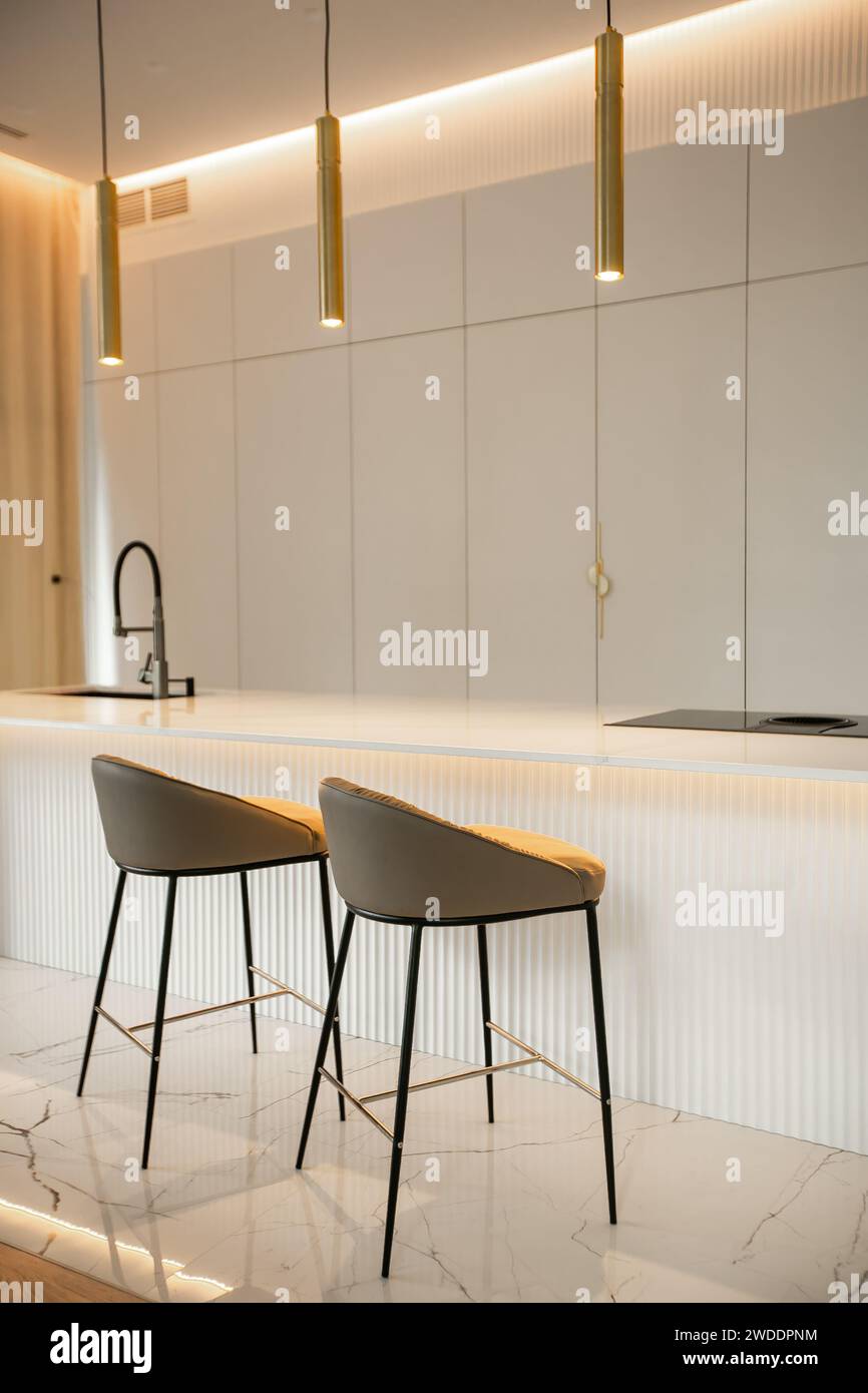 Minimalistic light interior of modern kitchen with island and high bar chairs Stock Photo