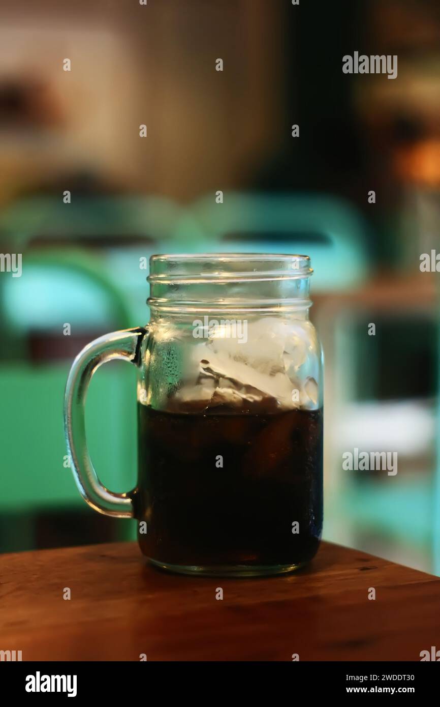 Close-up glass of cola with ice cubes on table of cafe Stock Photo