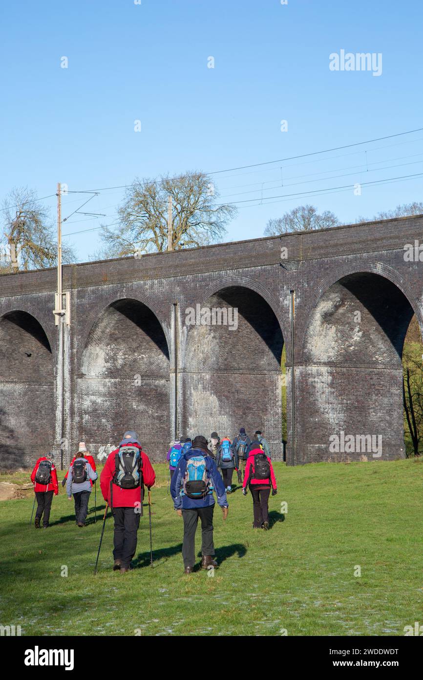 Group of ramblers walking in the Cheshire countryside  approaching the  railway Viaduct  over the river Dean near Wilmslow Cheshire Stock Photo