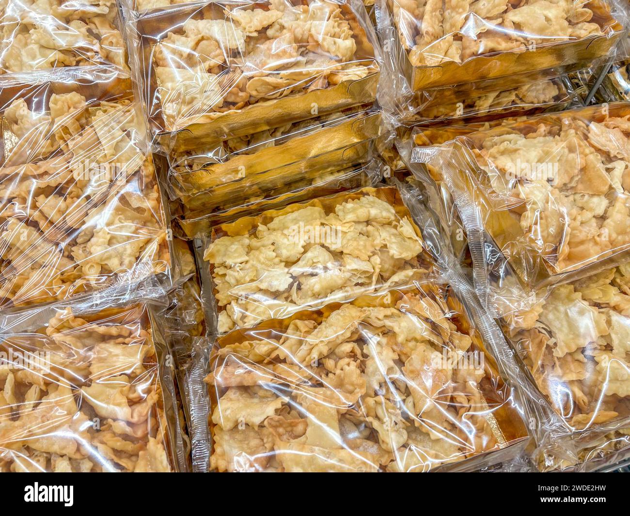 Bugie (Lies) or frappe or chiacchere or angel wings. Traditional italian carnival dessert in golden packages displayed for sale in market Stock Photo