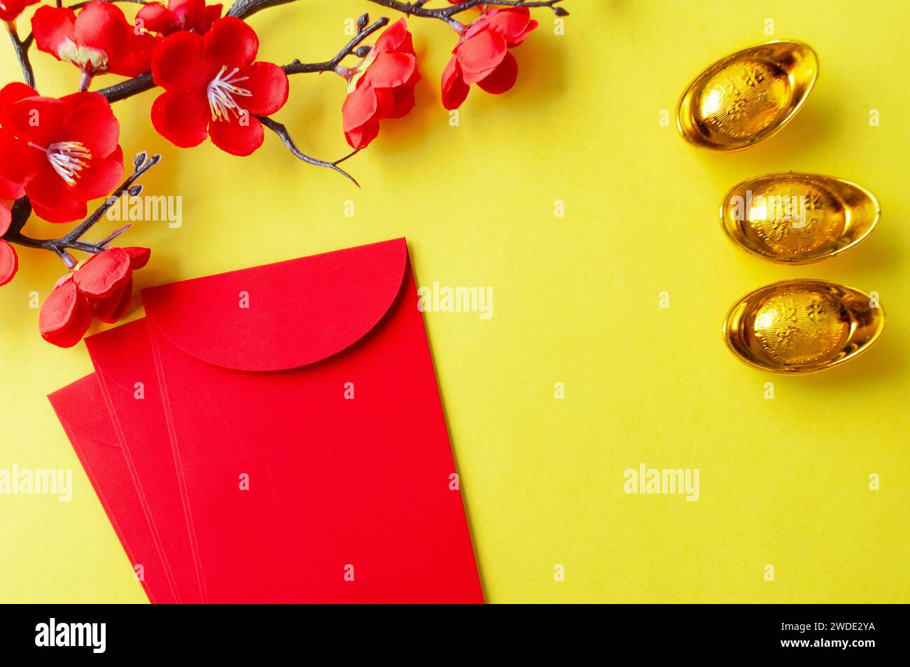 Top view of Chinese New Year red packet, cherry blossom and golden ingots decoration with customizable space for text or wishes. Stock Photo