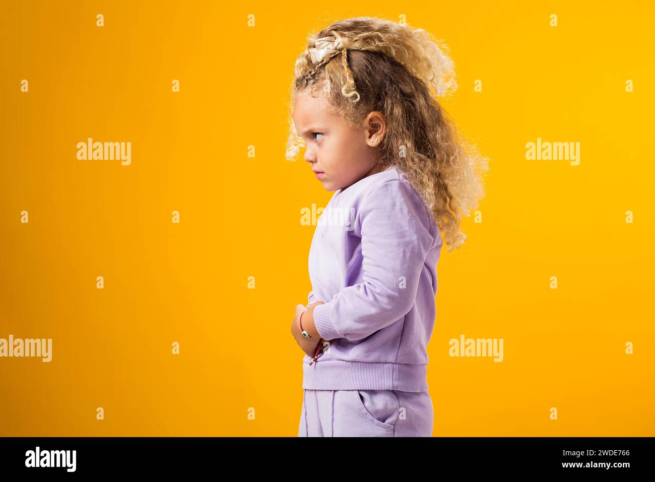 Portrait of child girl feeling abdominal pain, keeping hands on stomach because indigestion, painful illness feeling unwell. Ache concept. Stock Photo