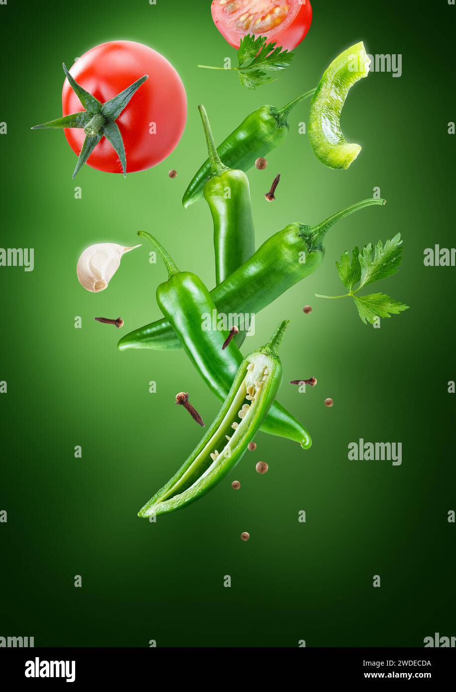 peppers with tomatoes in group flying on air stream on dark green background Stock Photo