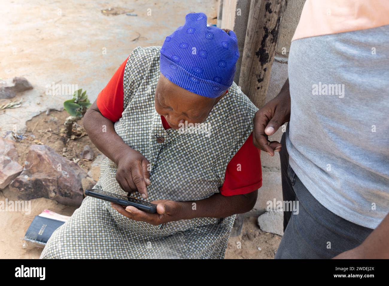 village african old woman learning to use a mobile phone with the help of a volunteer Stock Photo