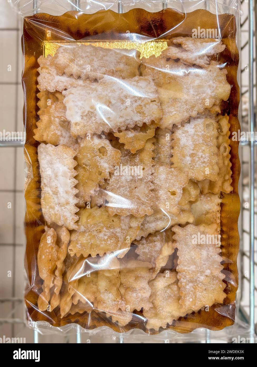Bugie (Lies) or frappe or chiacchere or angel wings. Traditional italian carnival dessert in golden package displayed for sale in market Stock Photo