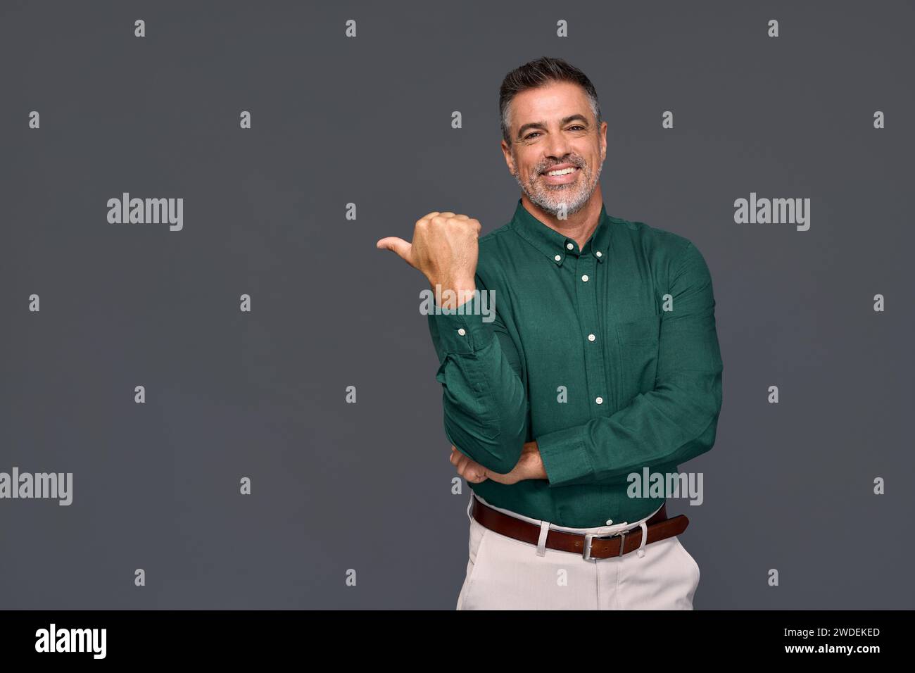 Happy older business man pointing aside advertising isolated on gray. Stock Photo