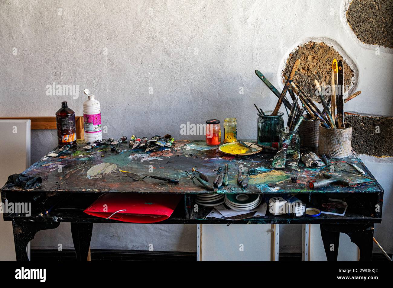Messy Artist's table with brushes and other art supplies in art studio Stock Photo