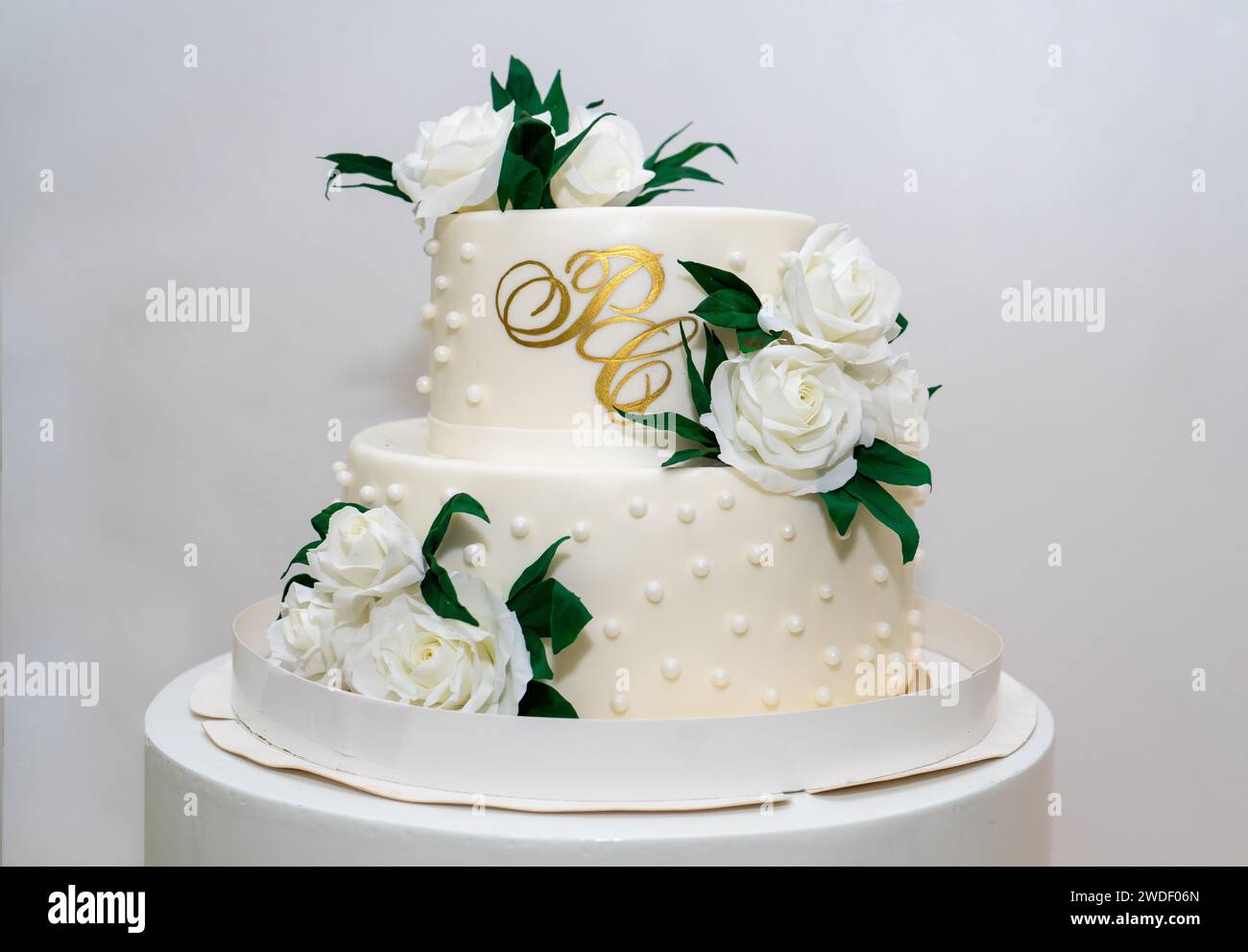 Two-tiered white wedding cake decorated with white roses Stock Photo ...