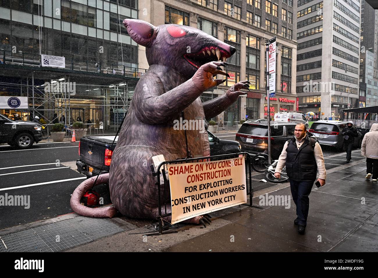 A giant inflatable rat stands outside a building on Broadway on January