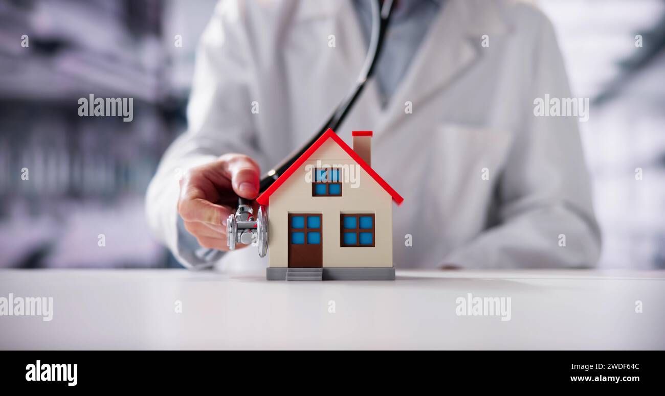 Close-up Of A Doctor's Hand Holding Stethoscope On House Model Stock Photo