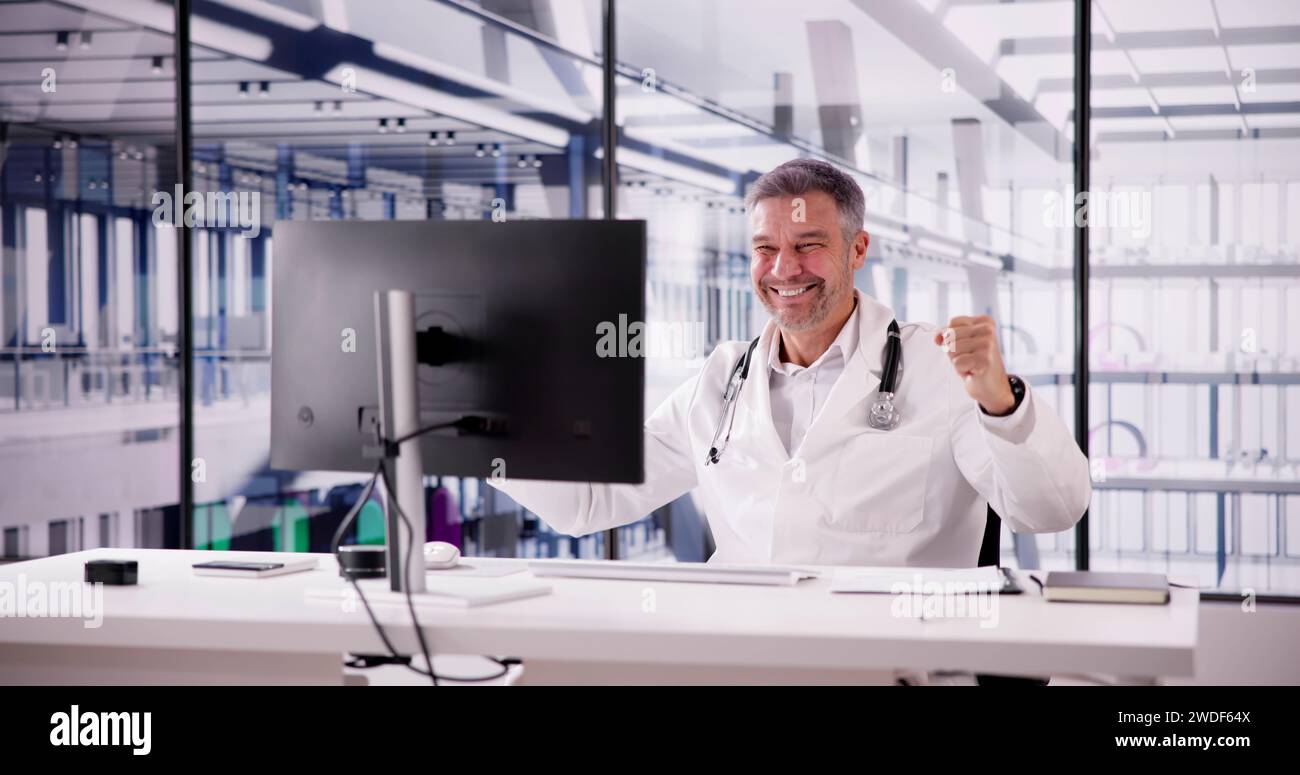 Portrait Of Confident Male Doctor Using Computer At Desk In Clinic Stock Photo