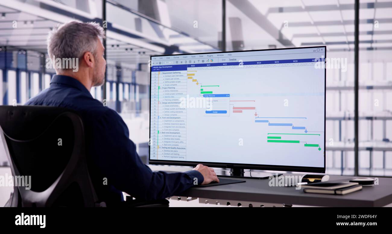 Businessman Working On Gantt Chart Using Computer On Office Desk Stock Photo