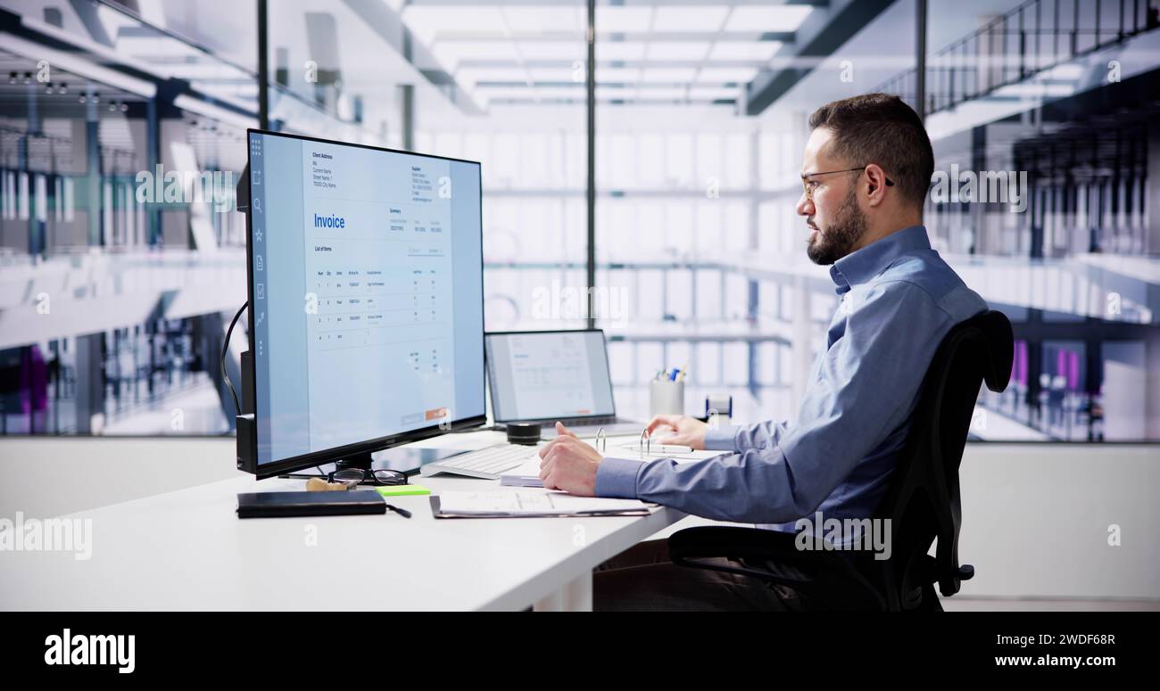 Businessperson Analyzing Invoice On Computer In Office Stock Photo