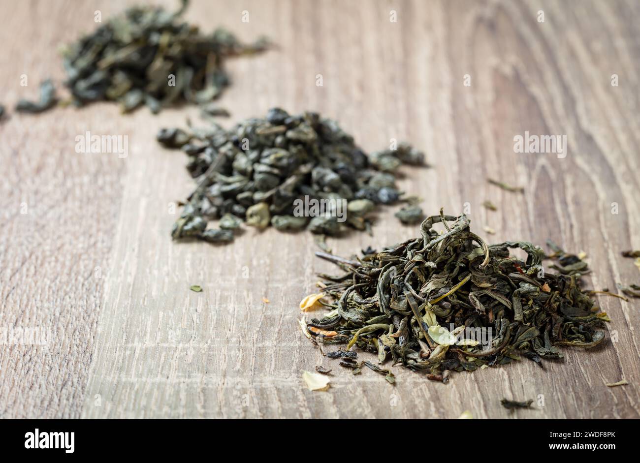 green tea leaves  on a wooden background; dried Chinese green tea long leaves;three small bunches Stock Photo