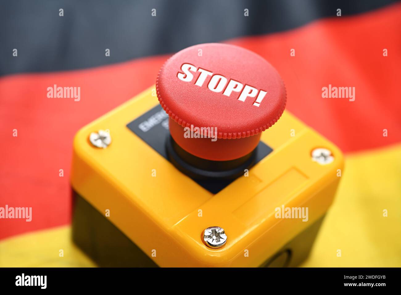 FOTOMONTAGE, Roter Knopf mit Aufschrift Stopp auf einer Deutschlandfahne *** FOTOMONTAGE, Red button with the word Stop on a German flag Stock Photo