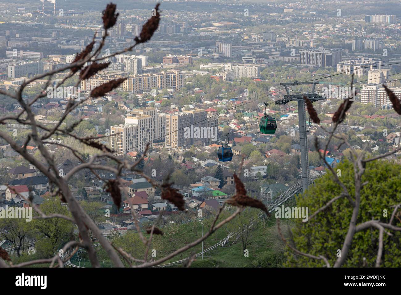 Aerial lift to Kok Tobe hill in Kazakhstan. Cable car with two cabins, against the backdrop of Almaty city at spring time. Tourist place, city landmar Stock Photo