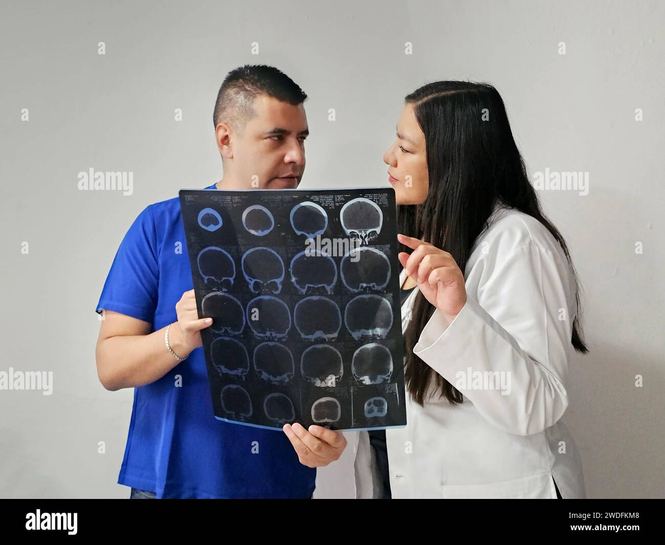 Latina neurologist specialist doctor woman and dark-skinned male nurse review patient's brain x-ray to discuss extraordinary case study and research Stock Photo