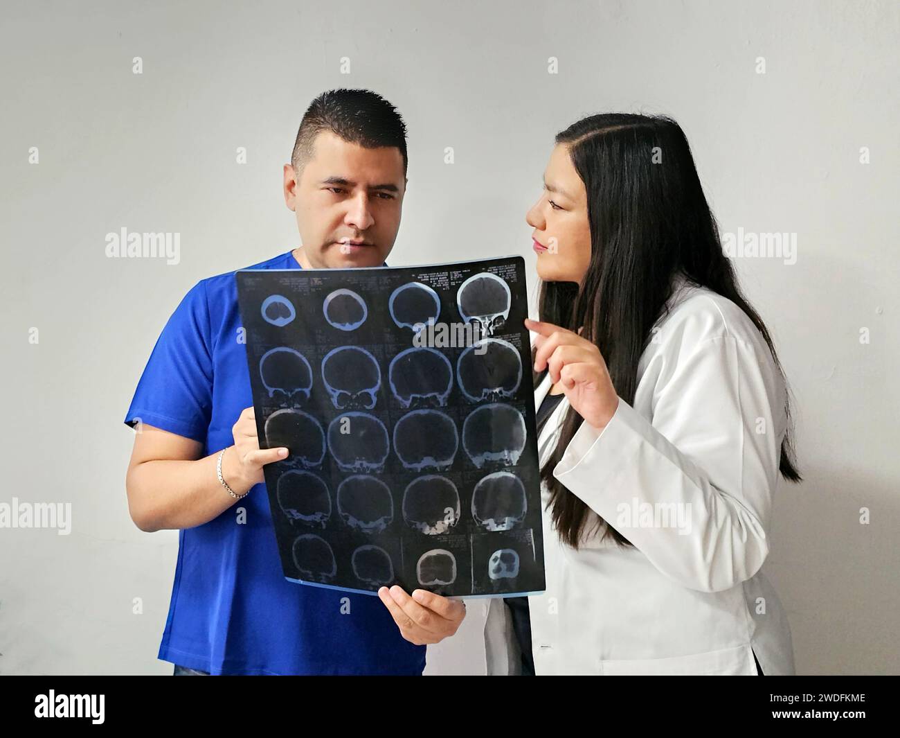 Latina neurologist specialist doctor woman and dark-skinned male nurse review patient's brain x-ray to discuss extraordinary case study and research Stock Photo