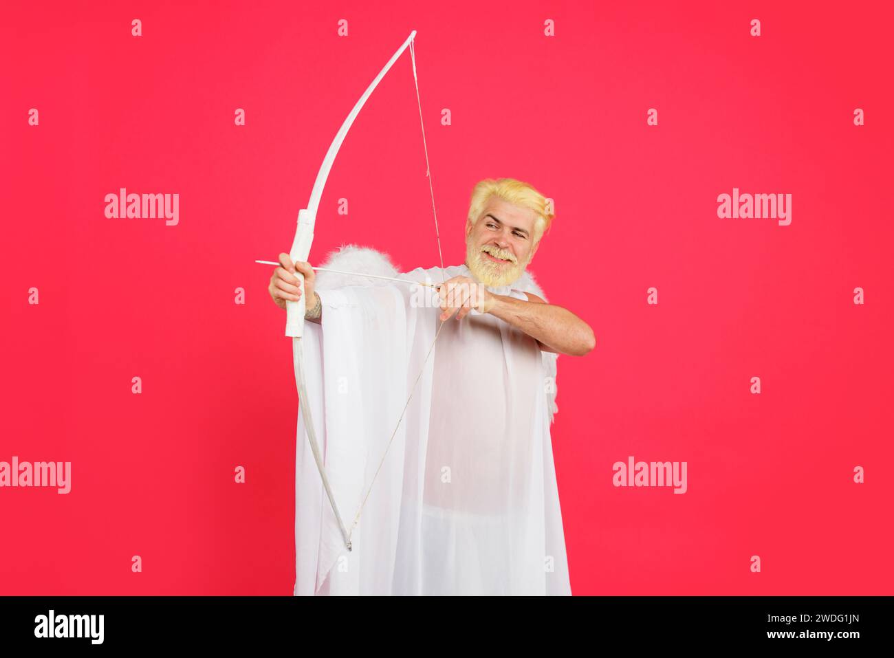 Valentines Day. Valentine cupid in angel wings aiming with bow. Amour. God of love. Smiling bearded man in angel costume with bow and arrow Stock Photo