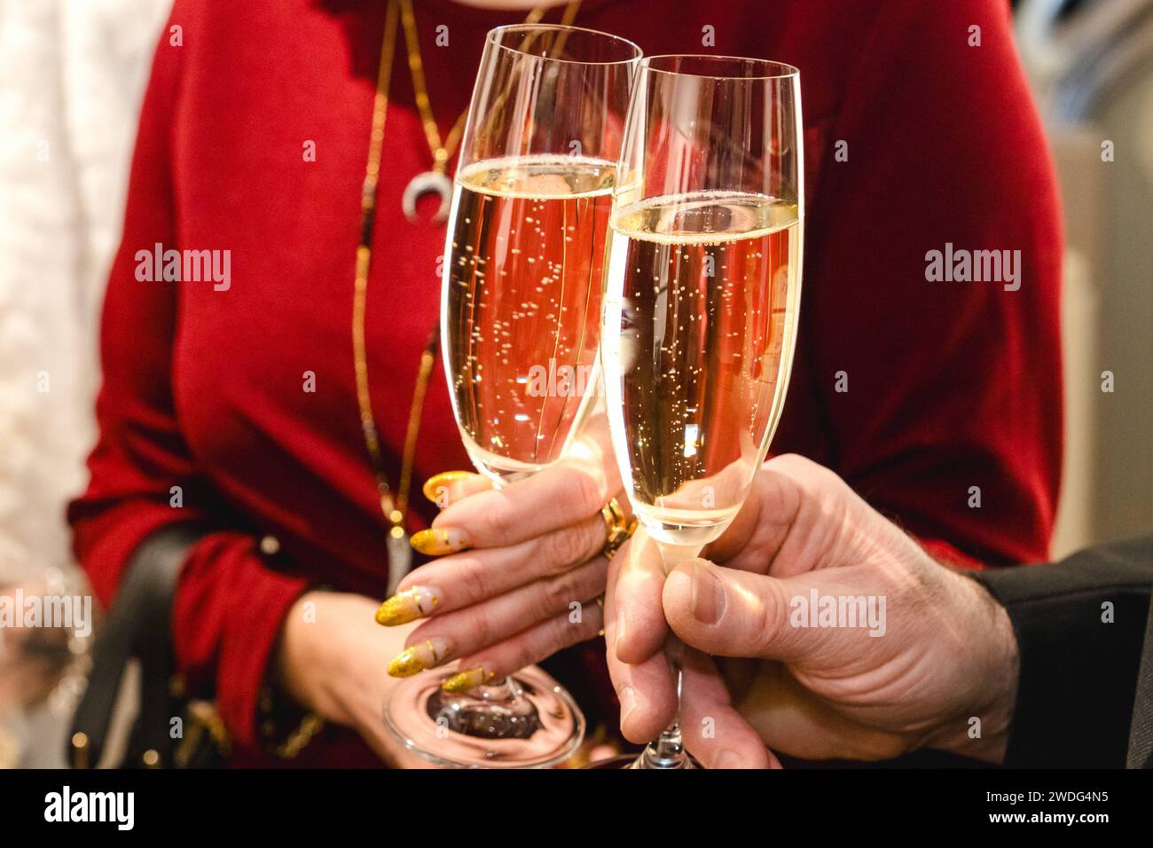Augsburg, Bavaria, Germany - January 19, 2024: Man and woman toast each other with a glass of champagne at a party *** Mann und Frau stoßen mit einem Glas Sekt bei einer Feier miteinander an Stock Photo