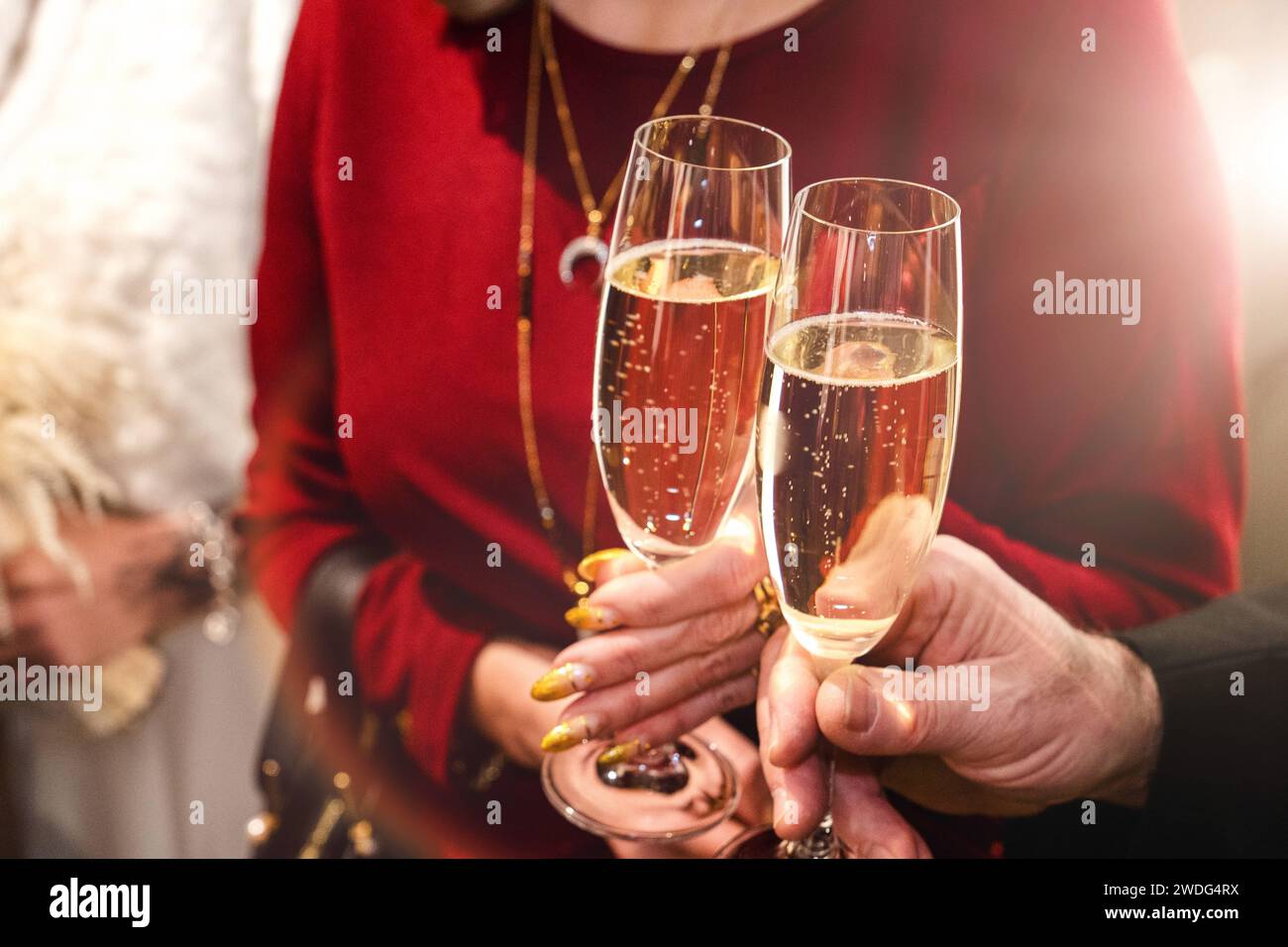 Augsburg, Bavaria, Germany - January 19, 2024: Man and woman toast each other with a glass of champagne at a party *** Mann und Frau stoßen mit einem Glas Sekt bei einer Feier miteinander an Stock Photo