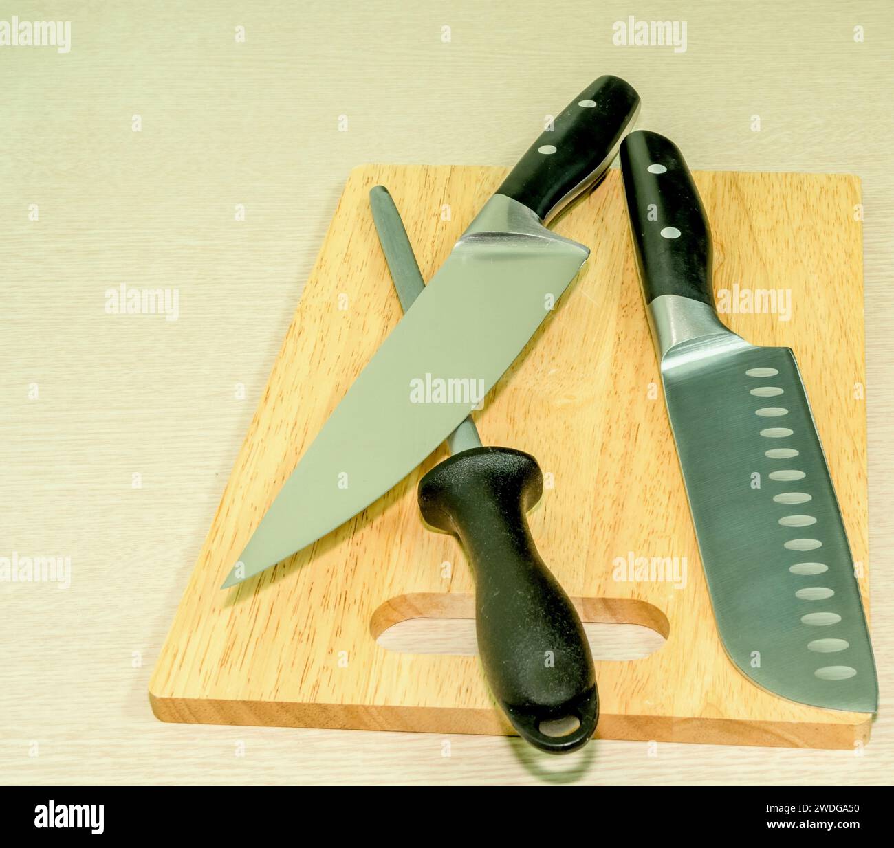 Chef's knife, Santoku knife and honing steel on woodblock cutting board