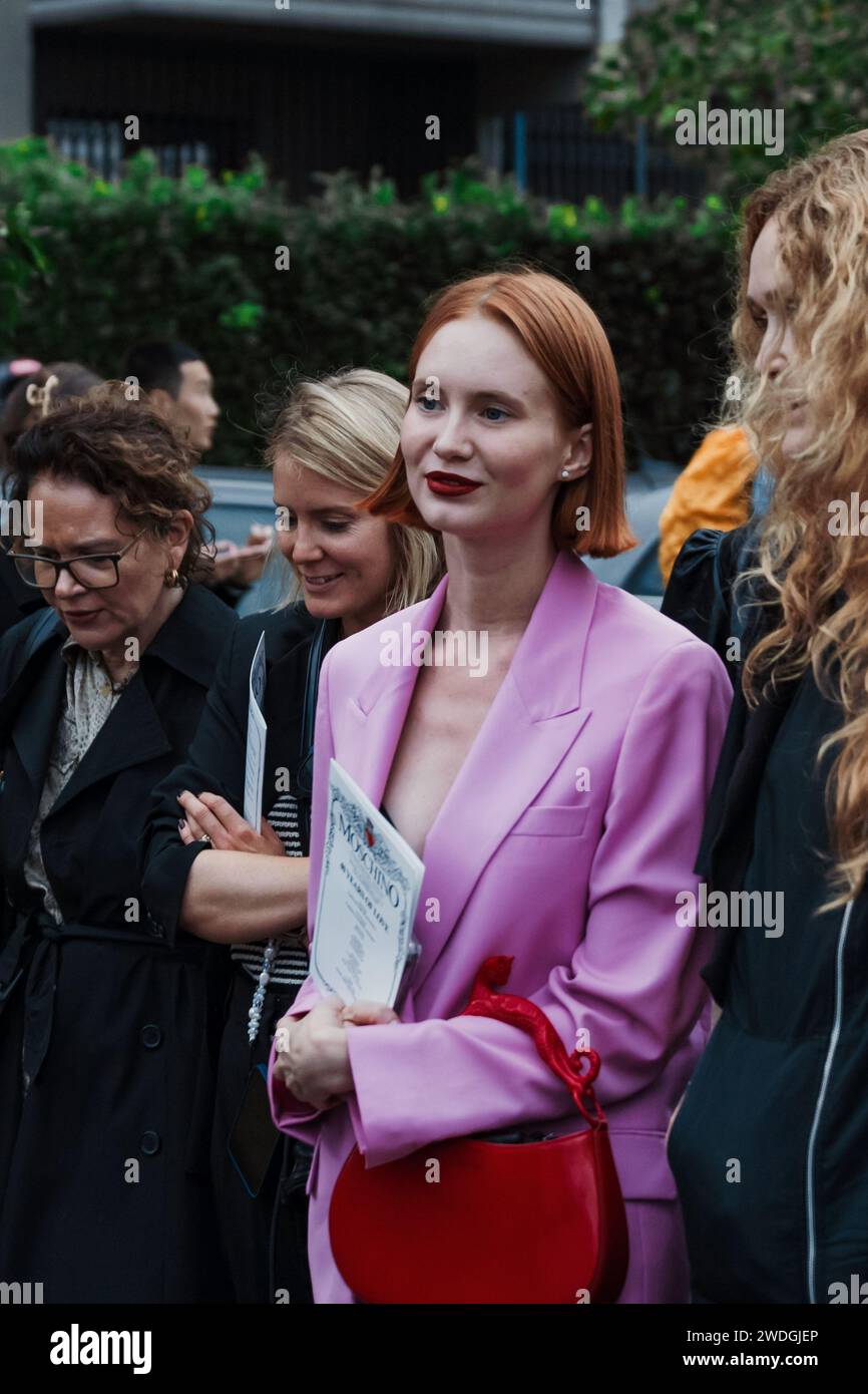 A guest wears a pink pantsuit, outside Moschino show during Milan Fashion Week Womenswear Spring/Summer 2024. Stock Photo