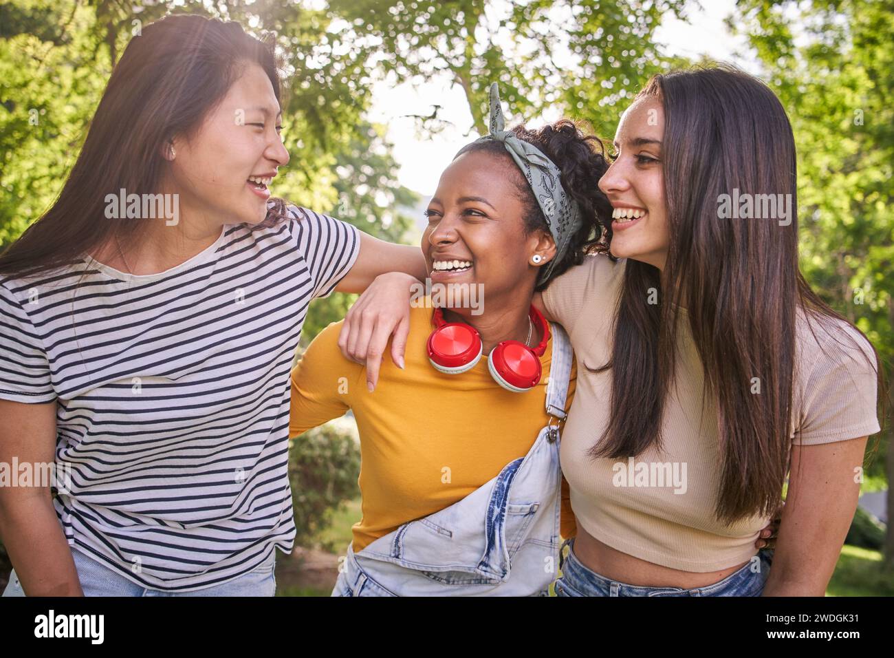 Group of young multicultural nice women laughing enjoying standing together in park on sunny day. Stock Photo