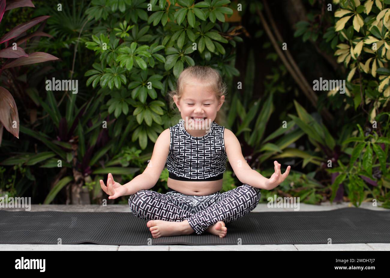 Little girl practicing yoga. Smiling child doing yoga practice. Meditation kids Stock Photo