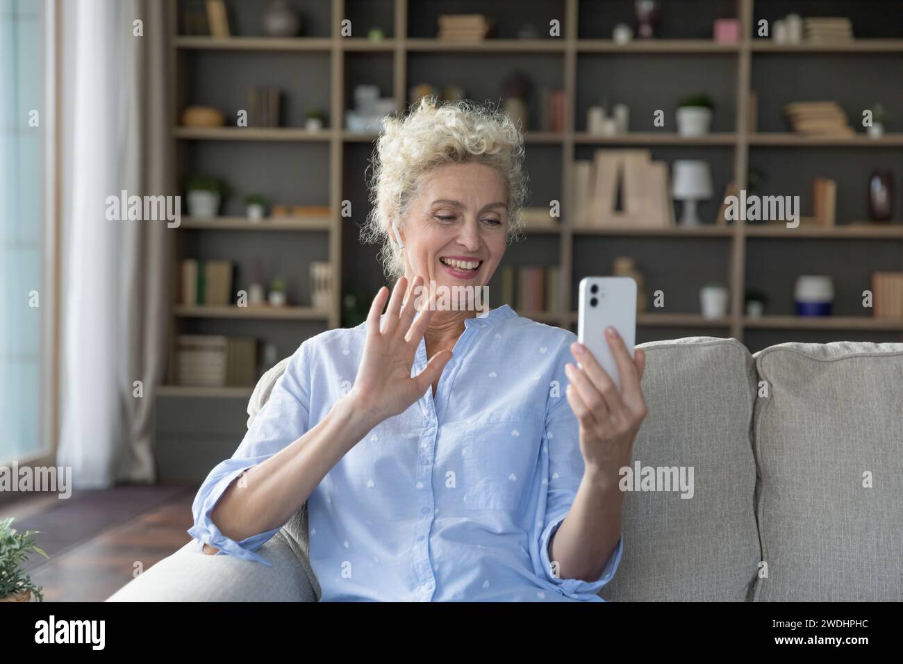 Smiling mature female make video call using smartphone Stock Photo