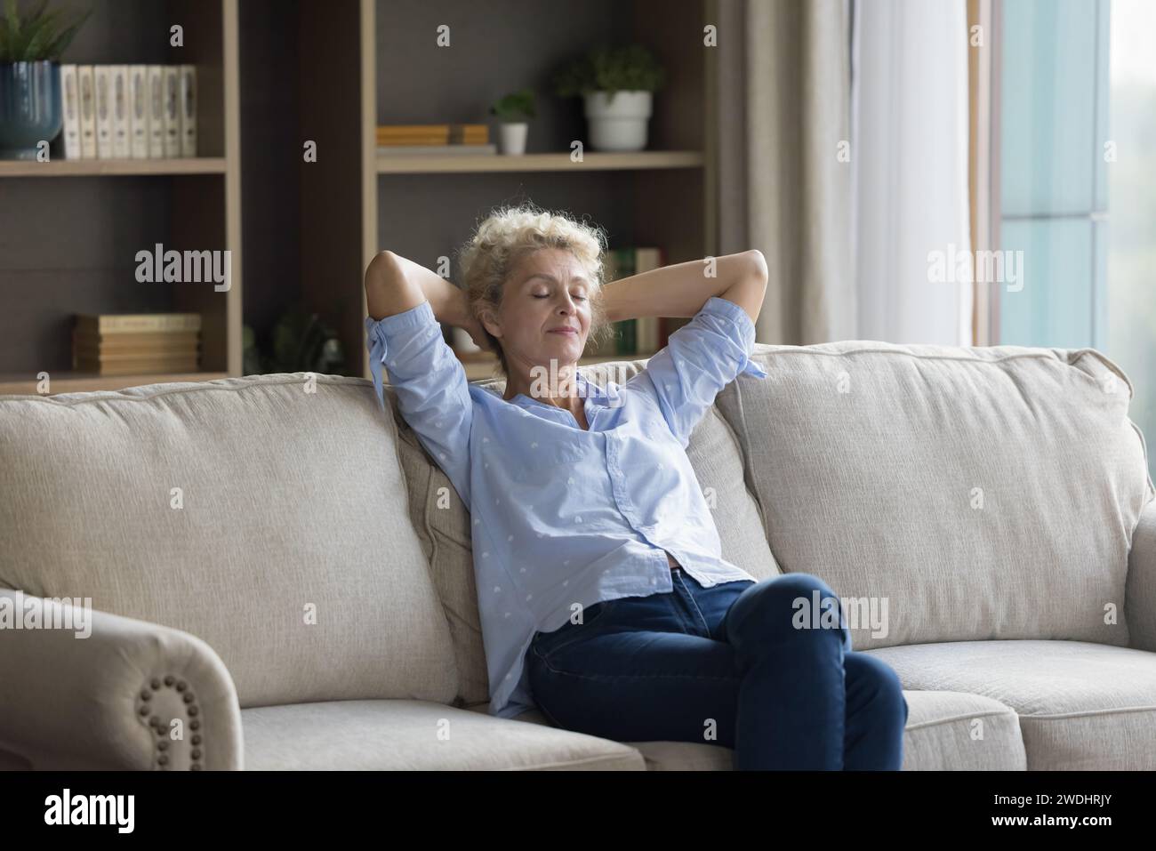 Silent peaceful middle-aged woman relaxing on sofa, take daytime break Stock Photo