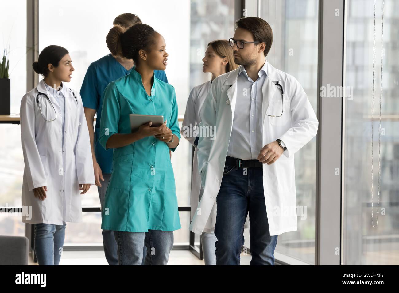 Diverse couple of young doctors walking in clinic office hall Stock Photo