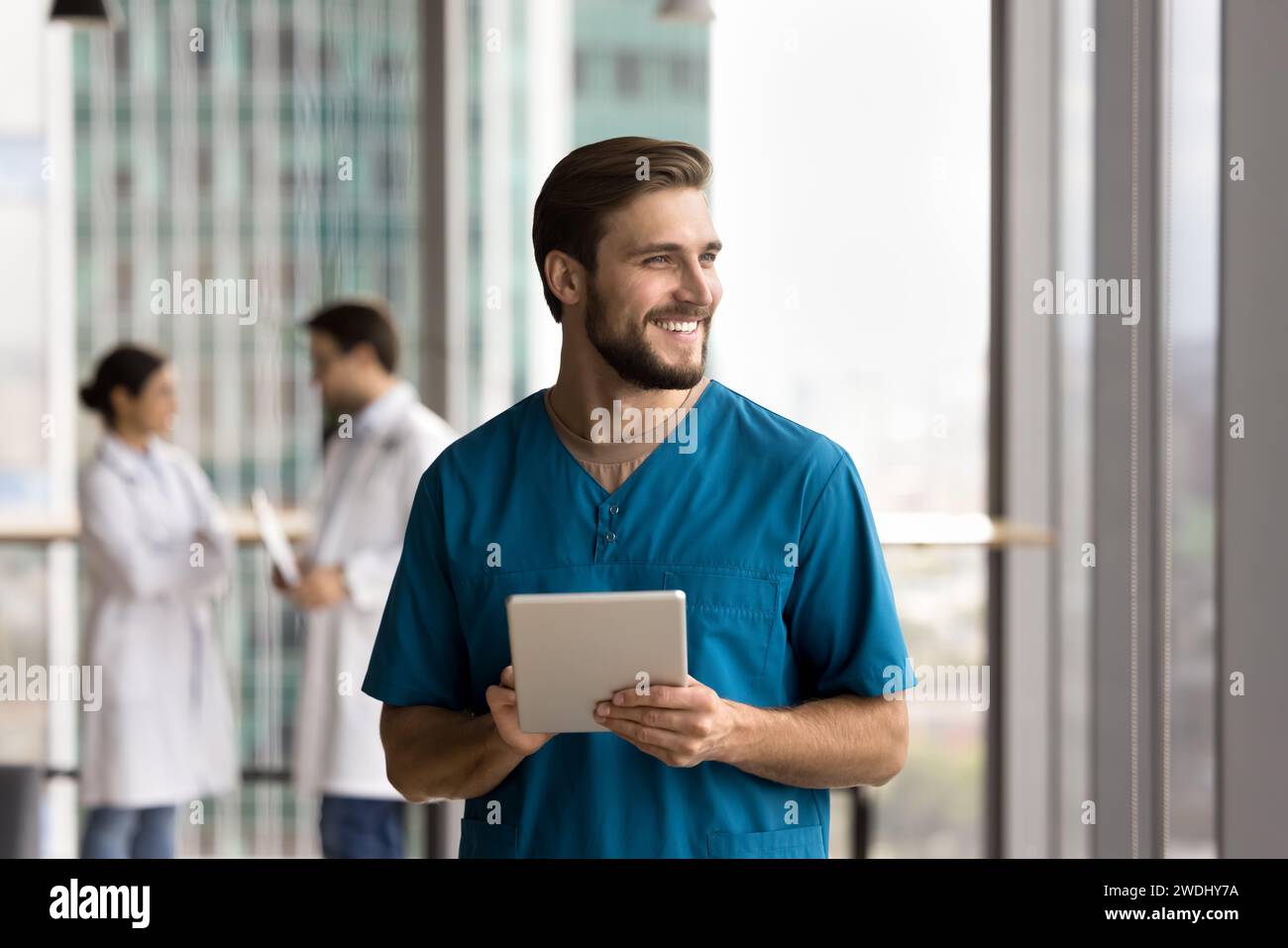 Happy handsome doctor man in blue uniform holding digital tablet Stock Photo