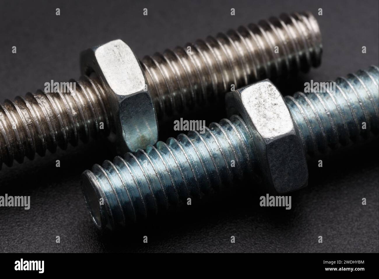 Two oxidized bolts with nuts close-up on a dark background. Macro photography Stock Photo