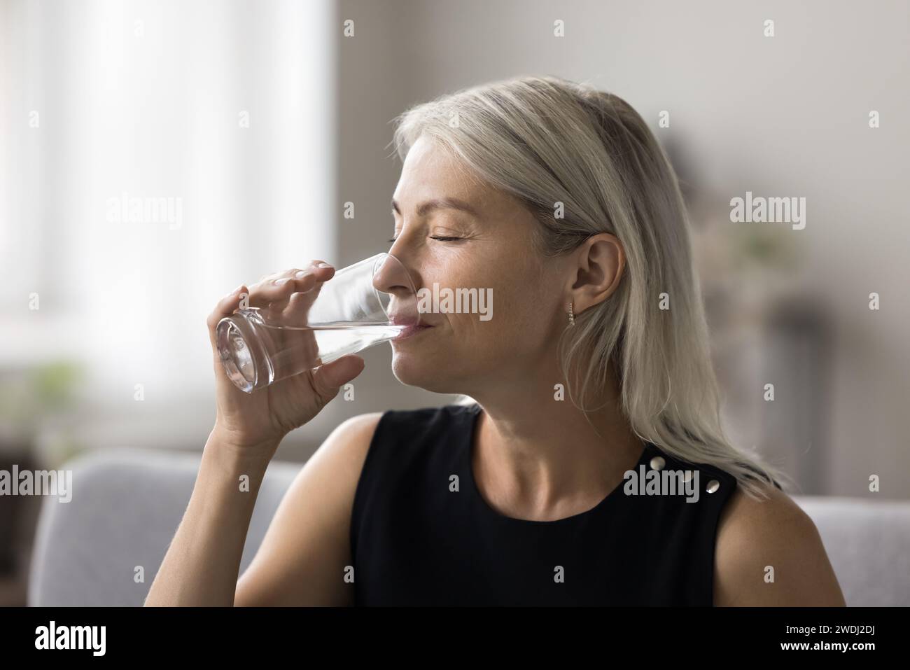 Middle-aged woman holding glass drink still water Stock Photo - Alamy