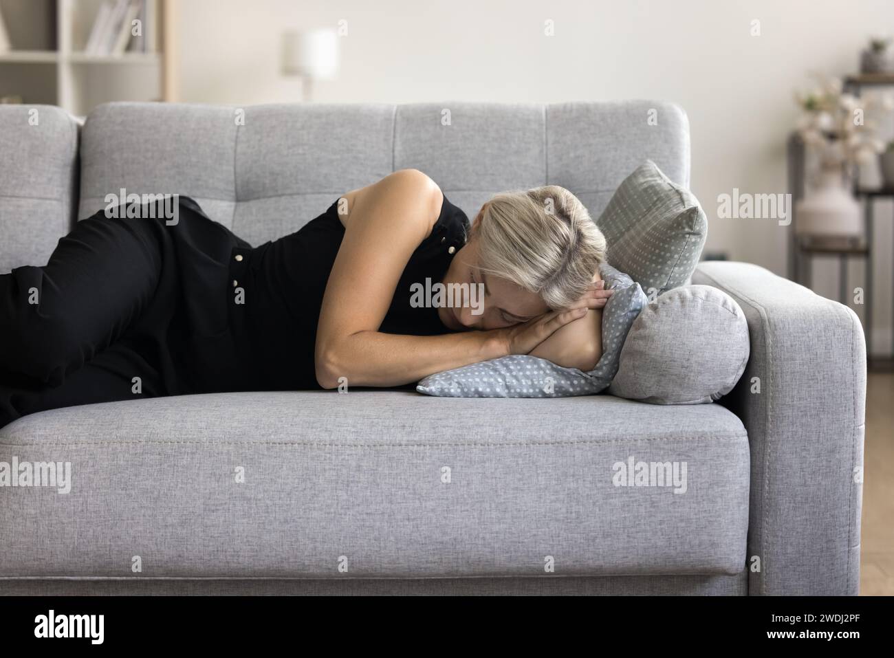 Woman lying on sofa take daytime nap in living room Stock Photo