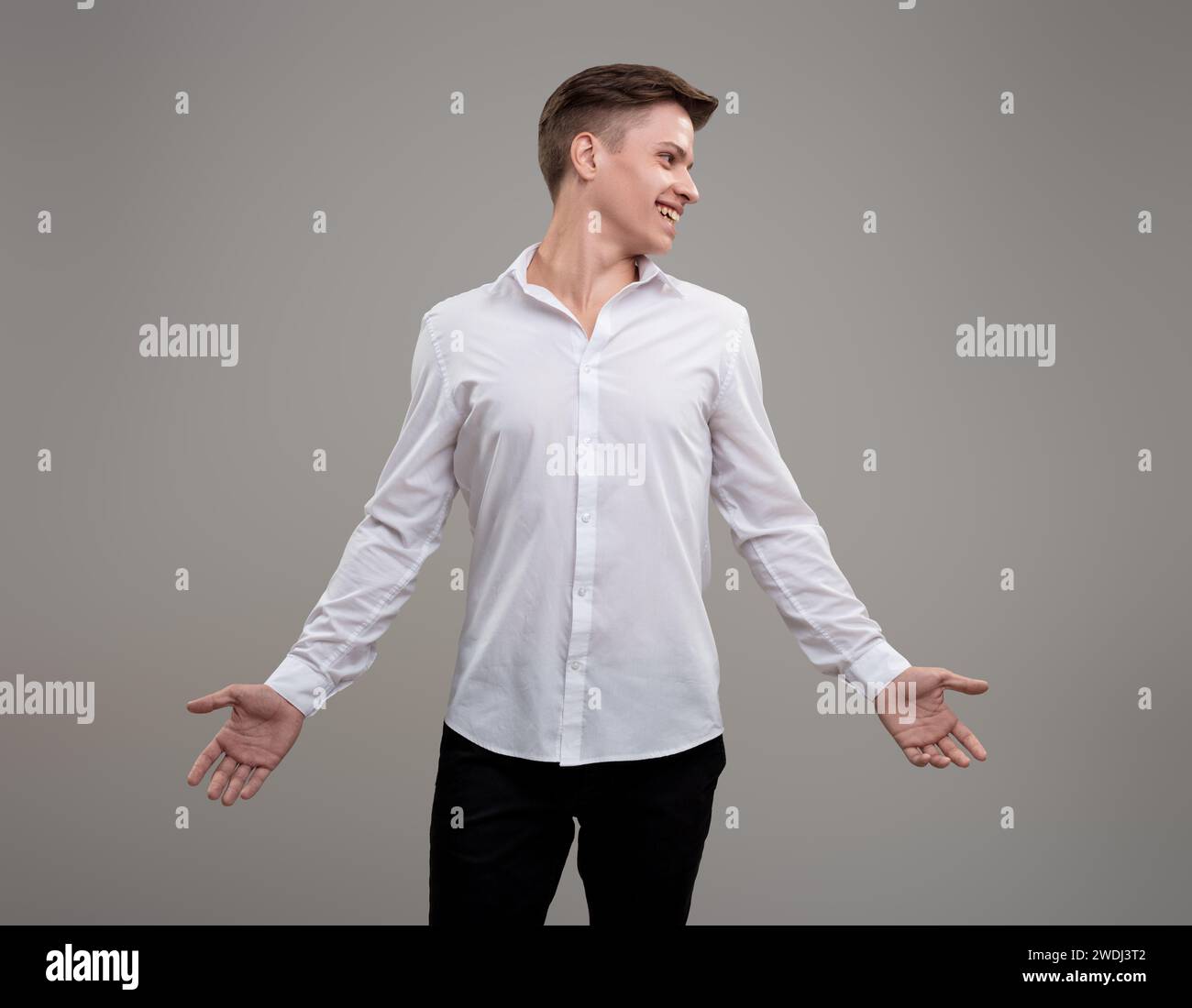 Personable man with arms outstretched presents an inviting posture, blending openness with a sharp outfit Stock Photo