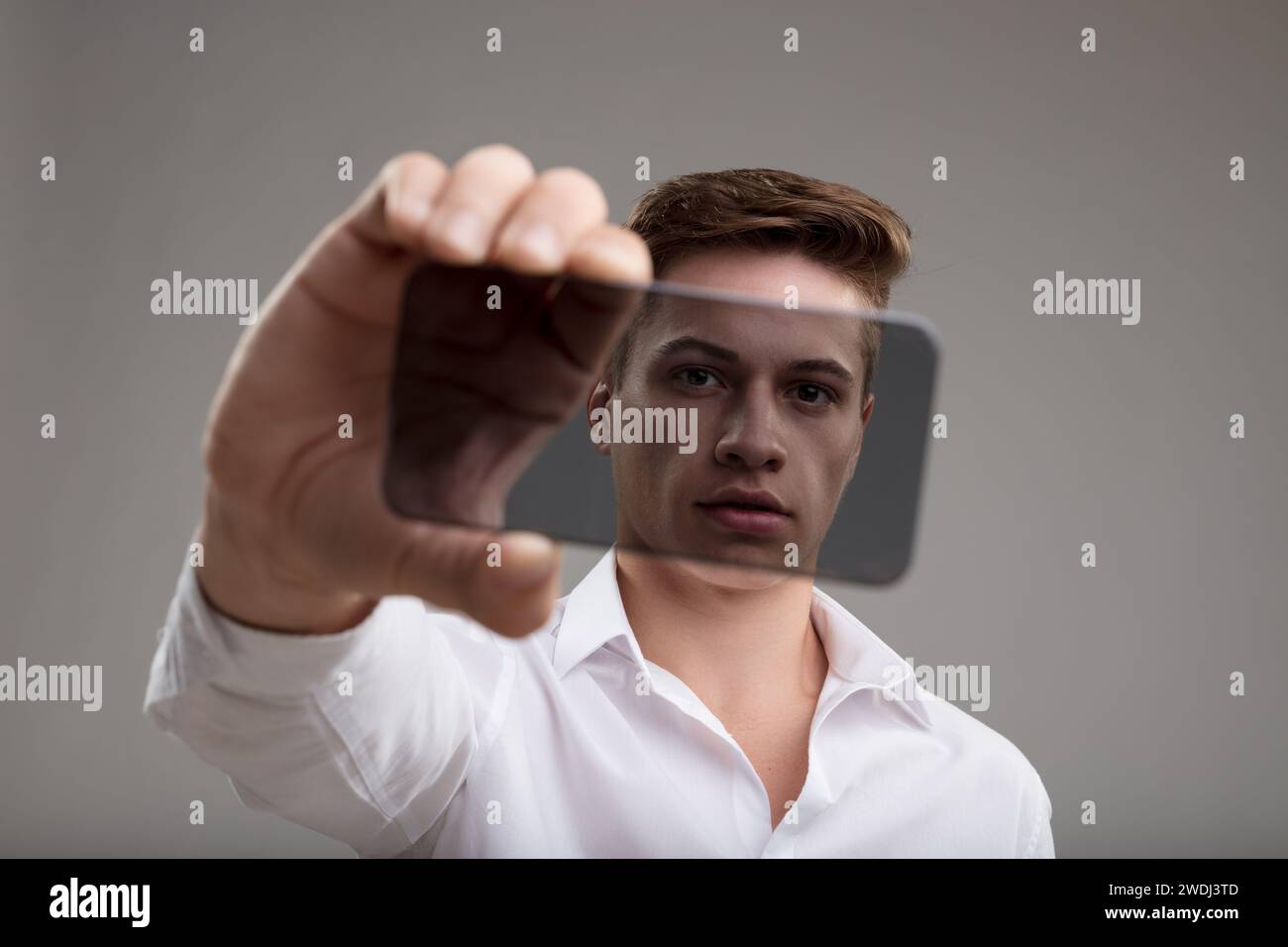 Man in white shirt showcases a transparent high-tech smartphone, symbolizing cutting-edge technology's transparency Stock Photo