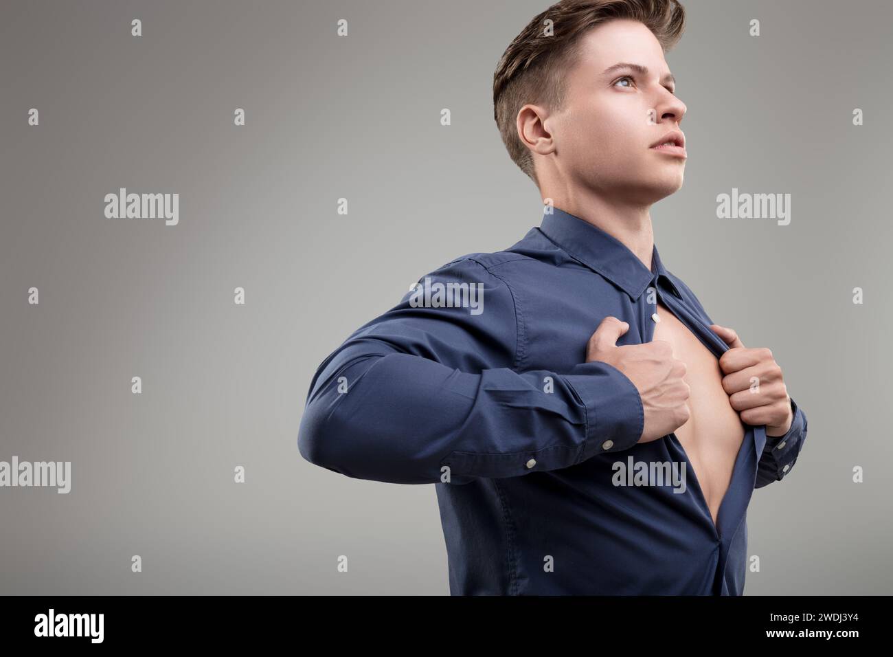 Dramatically opening his shirt, he showcases the strength that lies beneath the surface of everyday attire Stock Photo
