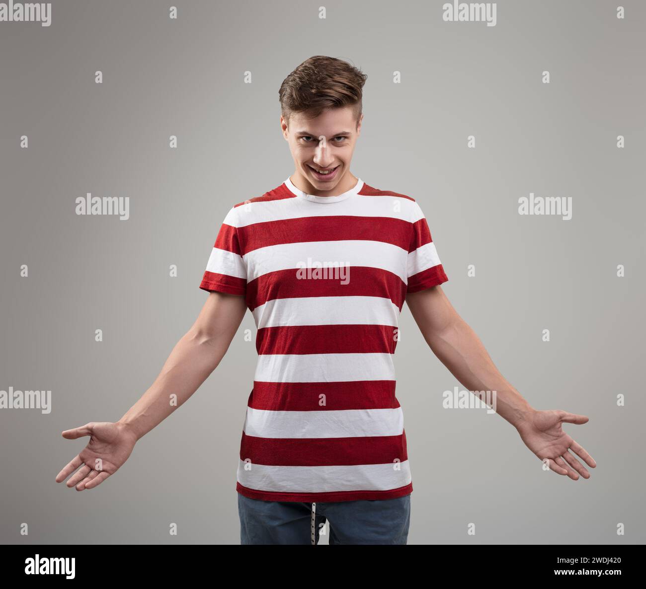 Casually dressed in stripes, his mischievous grin and shrug suggest a lighthearted, easygoing personality Stock Photo