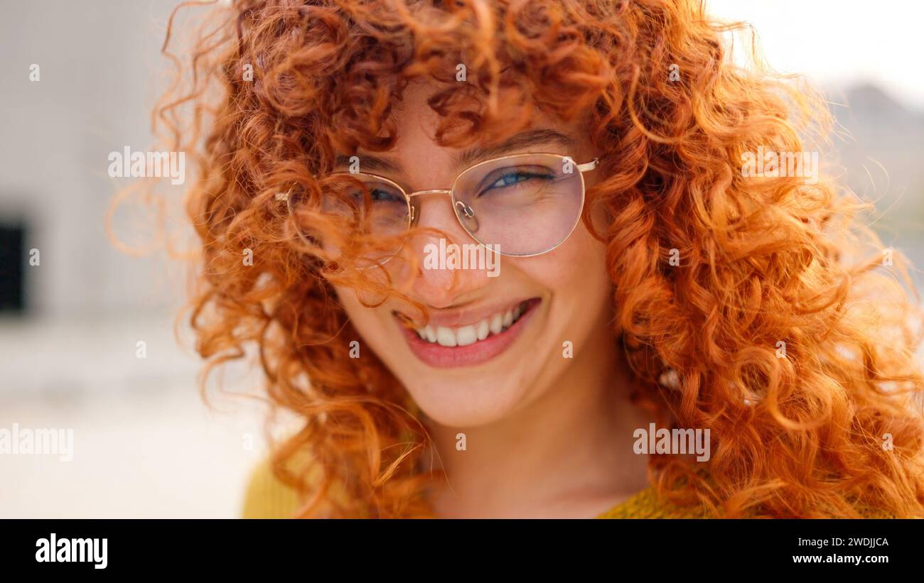 Redhead woman with curly long hair smiling at camera Stock Photo
