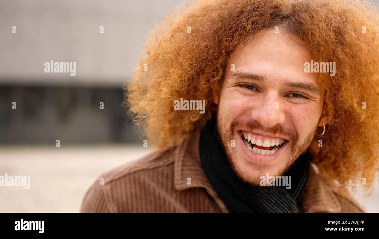 Young man with curly hair smiling at camera Stock Photo