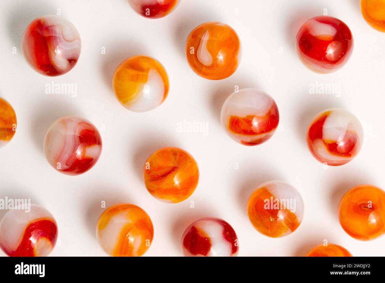 Red, orange, and white swirl glass marbles. Stock Photo