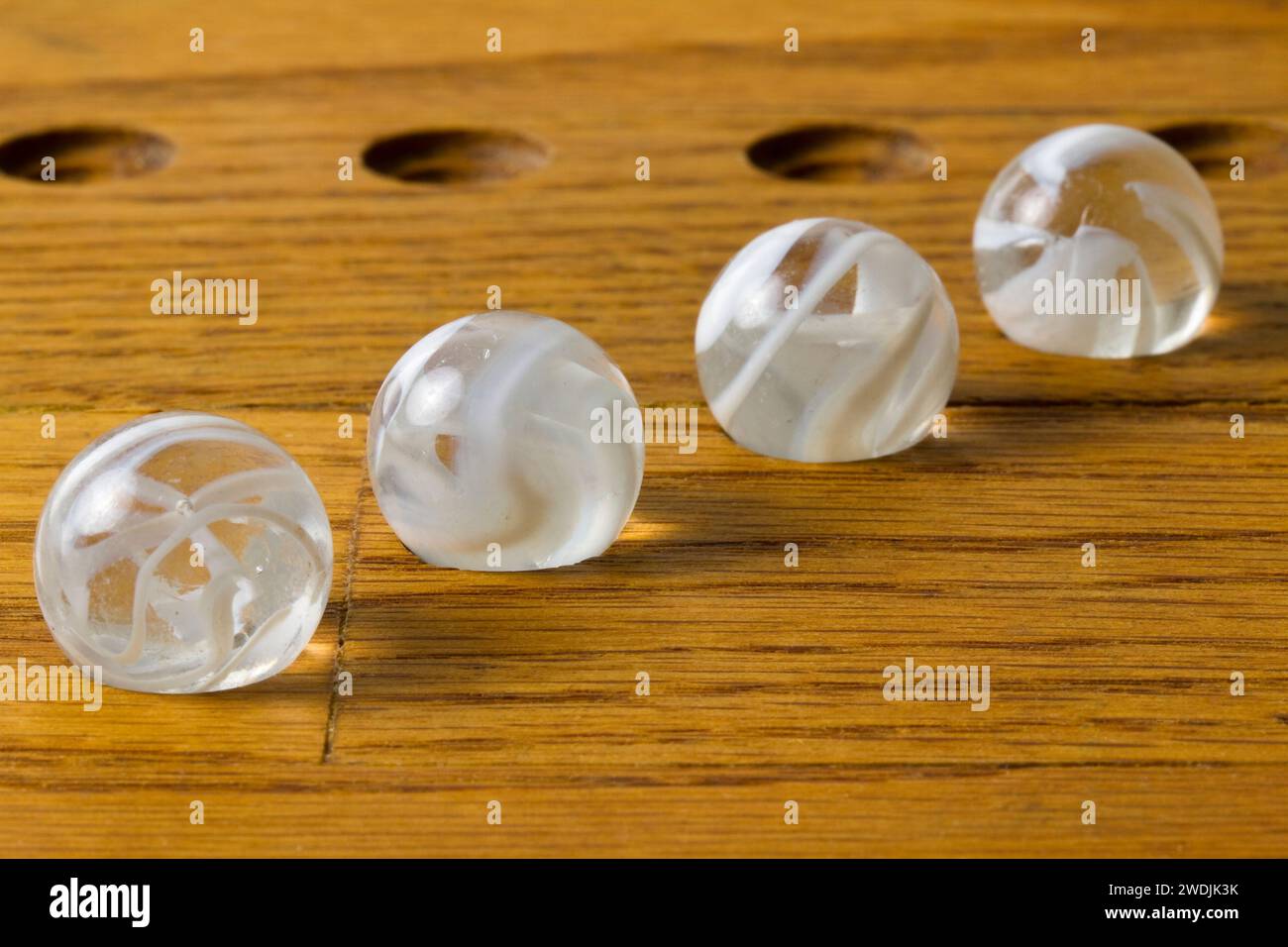 Four white swirl glass marbles on a wooden game board Stock Photo - Alamy
