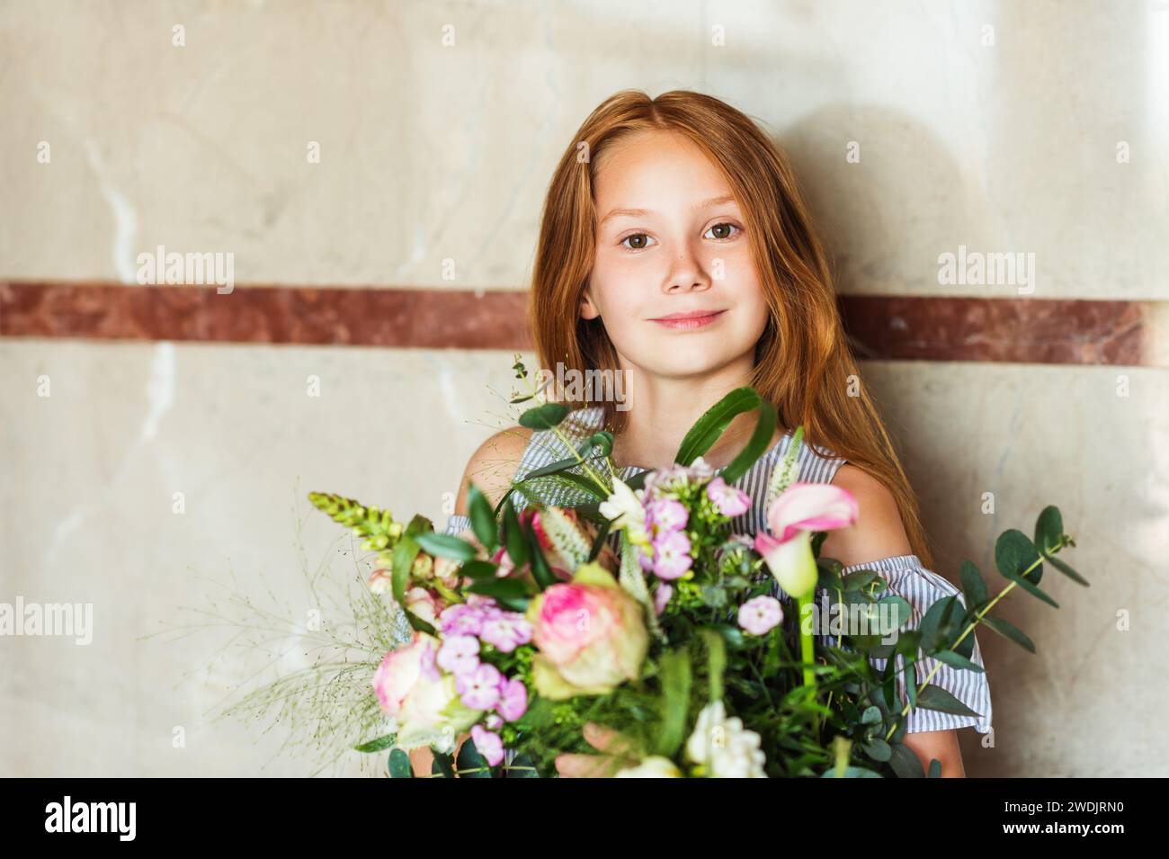 Close up portrait of adorable red hair kid girl holding big flower ...