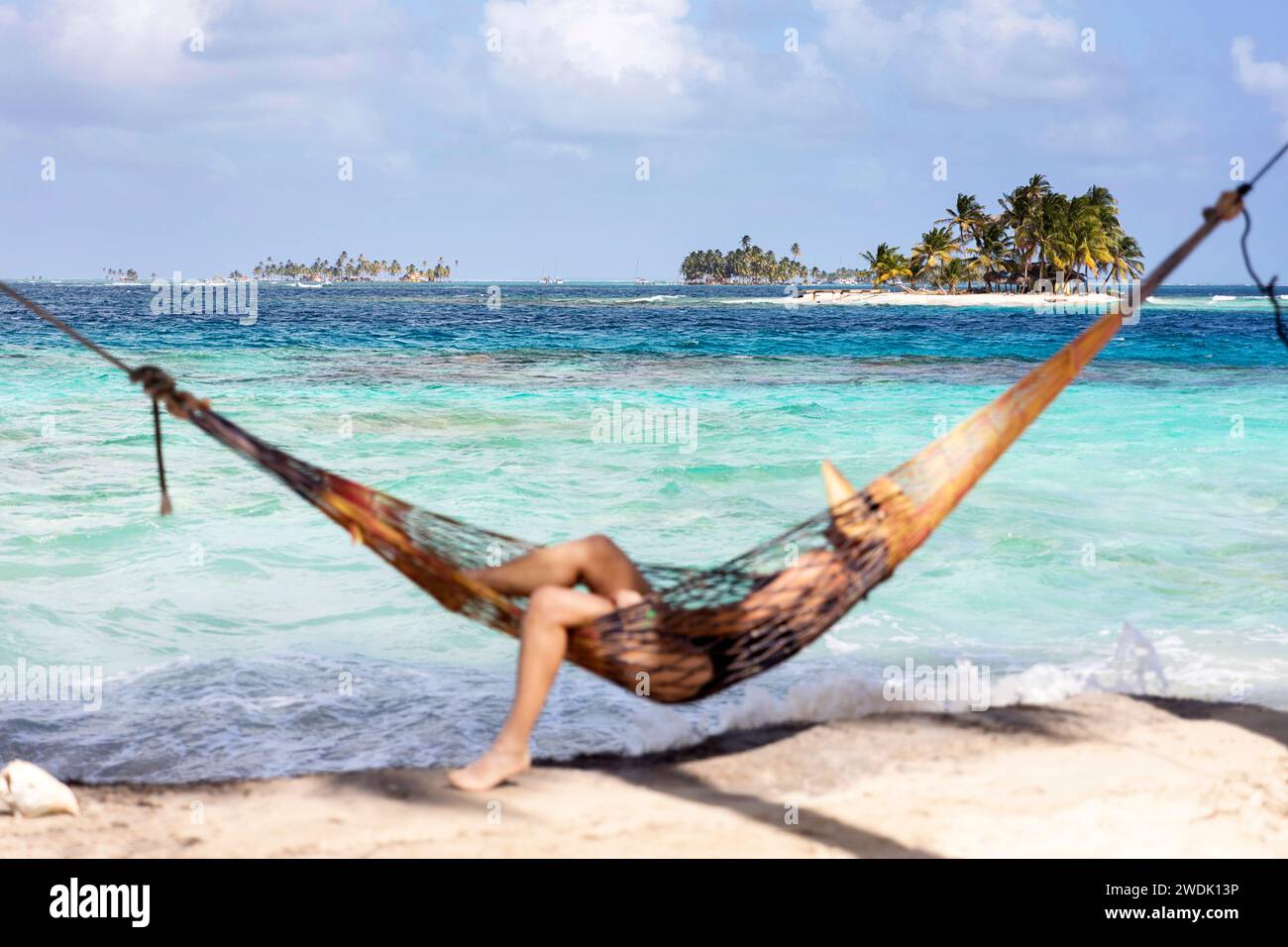 Woman tourist in a hammock with straw hat on her head relaxing on a idyllic tropical island in indigenous territory of Guna Yala in Panama Stock Photo