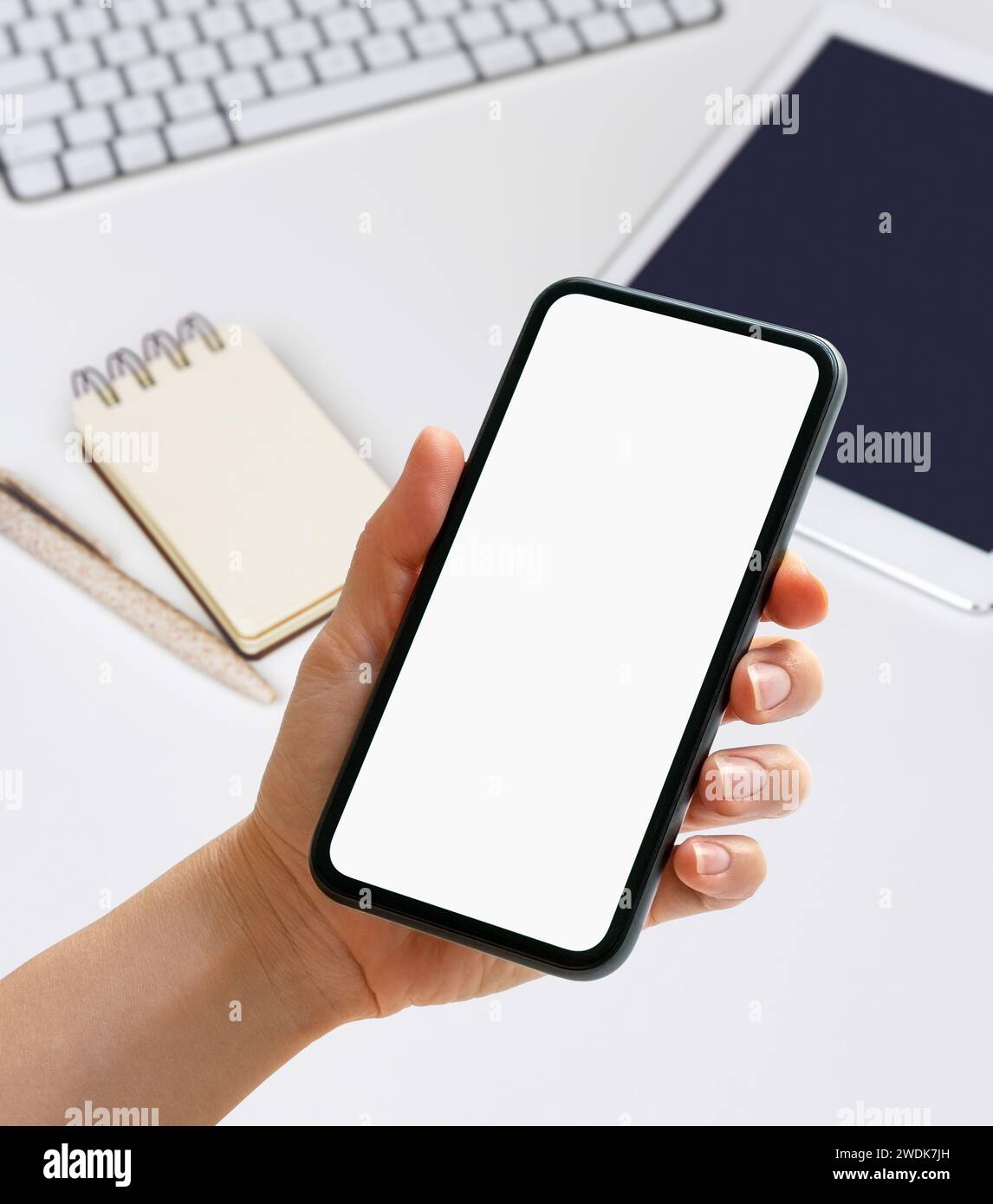 Mockup mobile app digital organizer. Hand holding phone with blank screen in front of diary, digital tablet and pc on the desk. Stock Photo