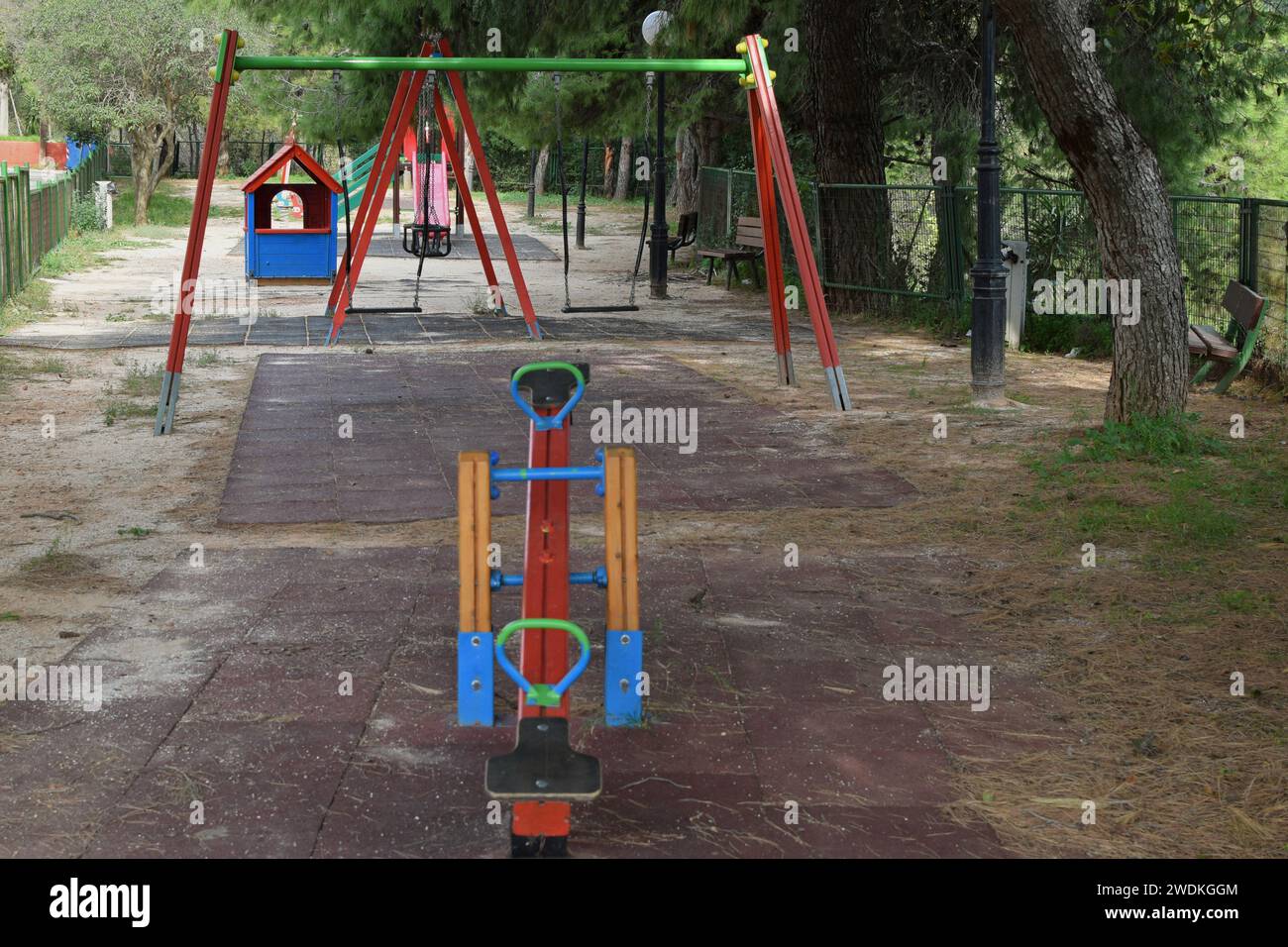 Swings and sitting benches in public playground park. Stock Photo
