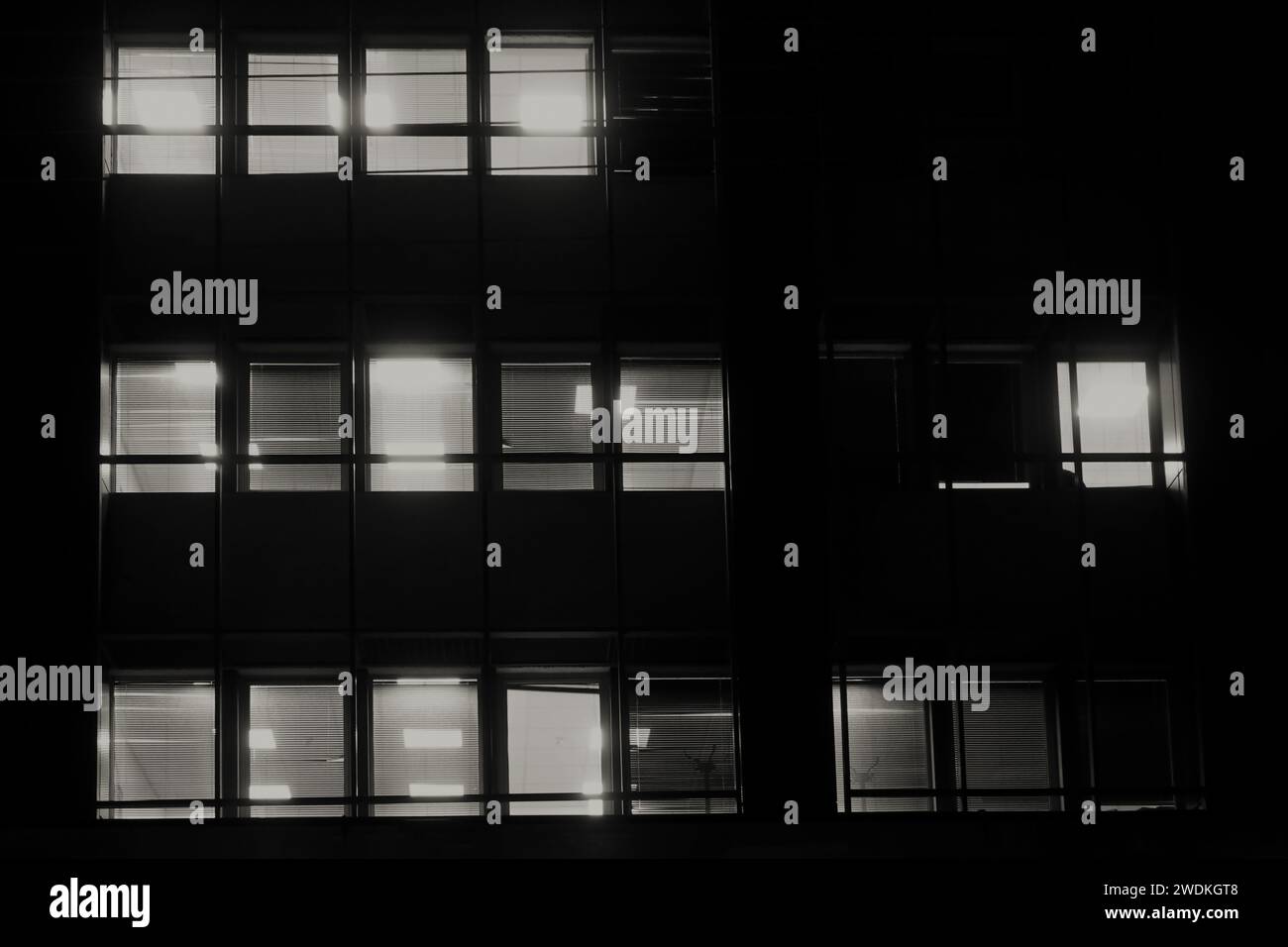Office building facade windows with venetian blinds at night. Stock Photo