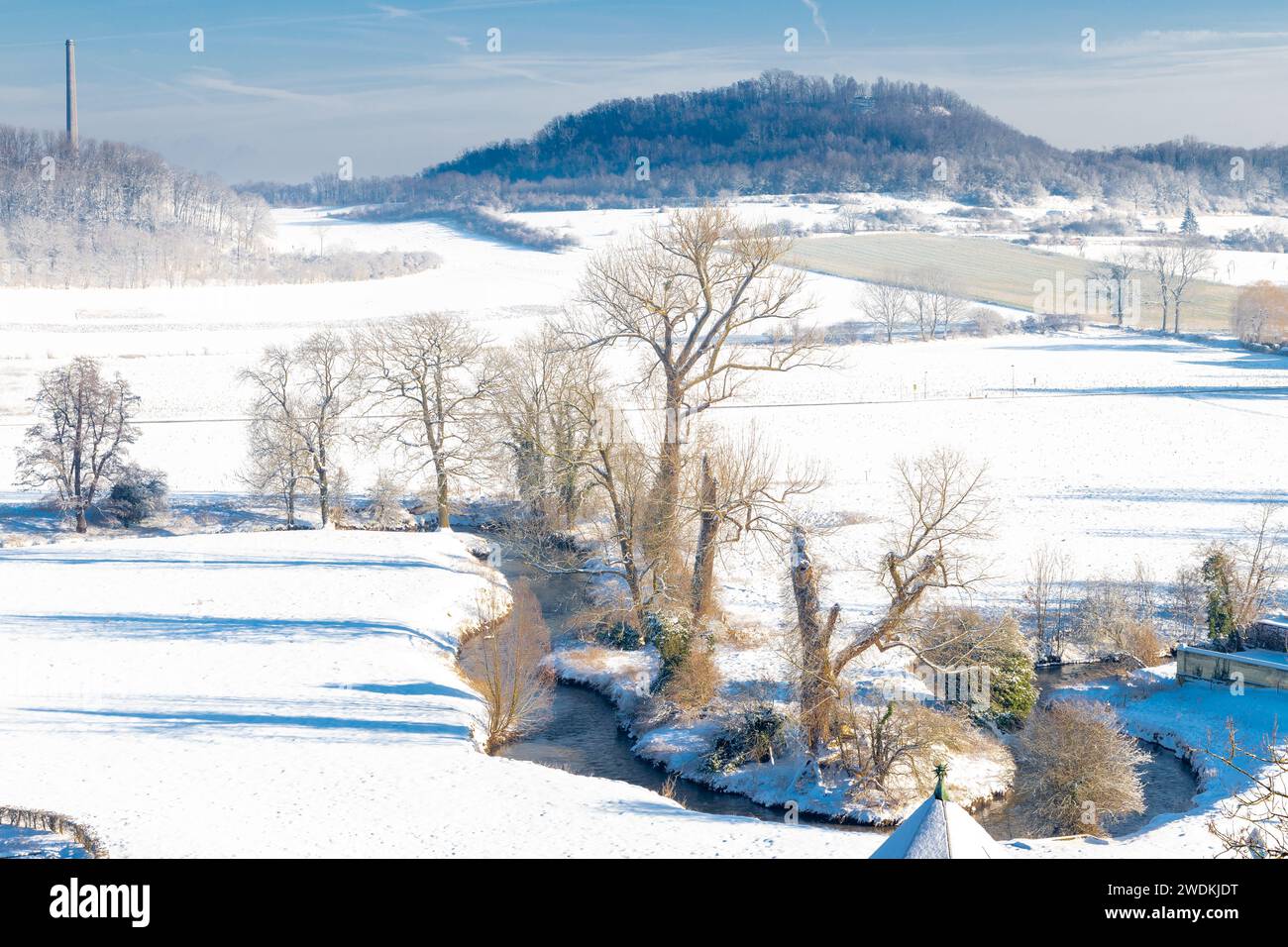 Winter landscape over the valley of Jekerdal just outside Maastricht, covered with fresh snow with a winding river through the scene and a forest in t Stock Photo